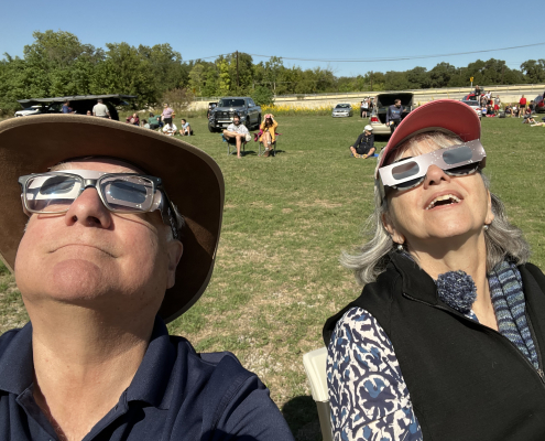 People wearing sunglasses, gazing up at an eclipse.