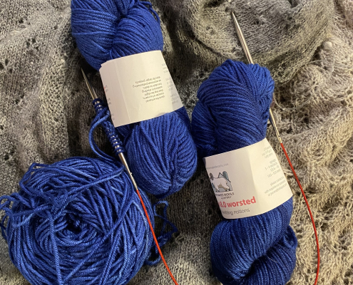 Royal blue knitting yarn sitting on hand-knit sweater