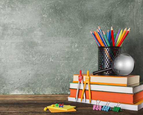 Stack of books and stationery on the background of the school board
