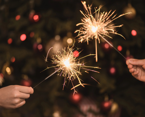Hands holding sparklers, reaching toward each other