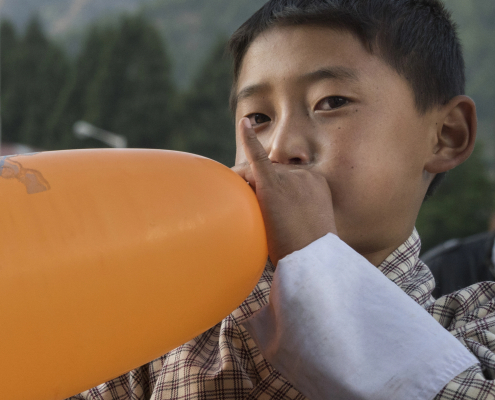 Boy blowing up an orange balloon
