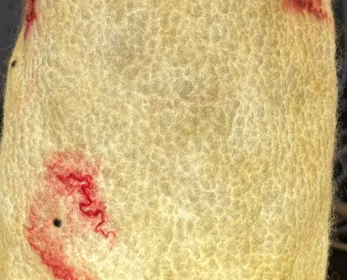 Handmade felt luminary, textured pale yellow wool, with red silk fibers here and there