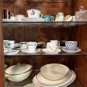 Glass shelves holding china and demitasse cups in a walnut cabinet
