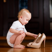 Baby sitting with heels on the ground looking at a pair of high heels