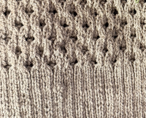 Light grey wool hand knit swatch, ribbing and an open work pattern