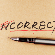 The word "incorrect" with the first two letters crossed out in red, and a pen beneath the word.