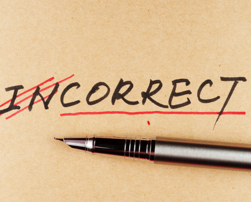 The word "incorrect" with the first two letters crossed out in red, and a pen beneath the word.