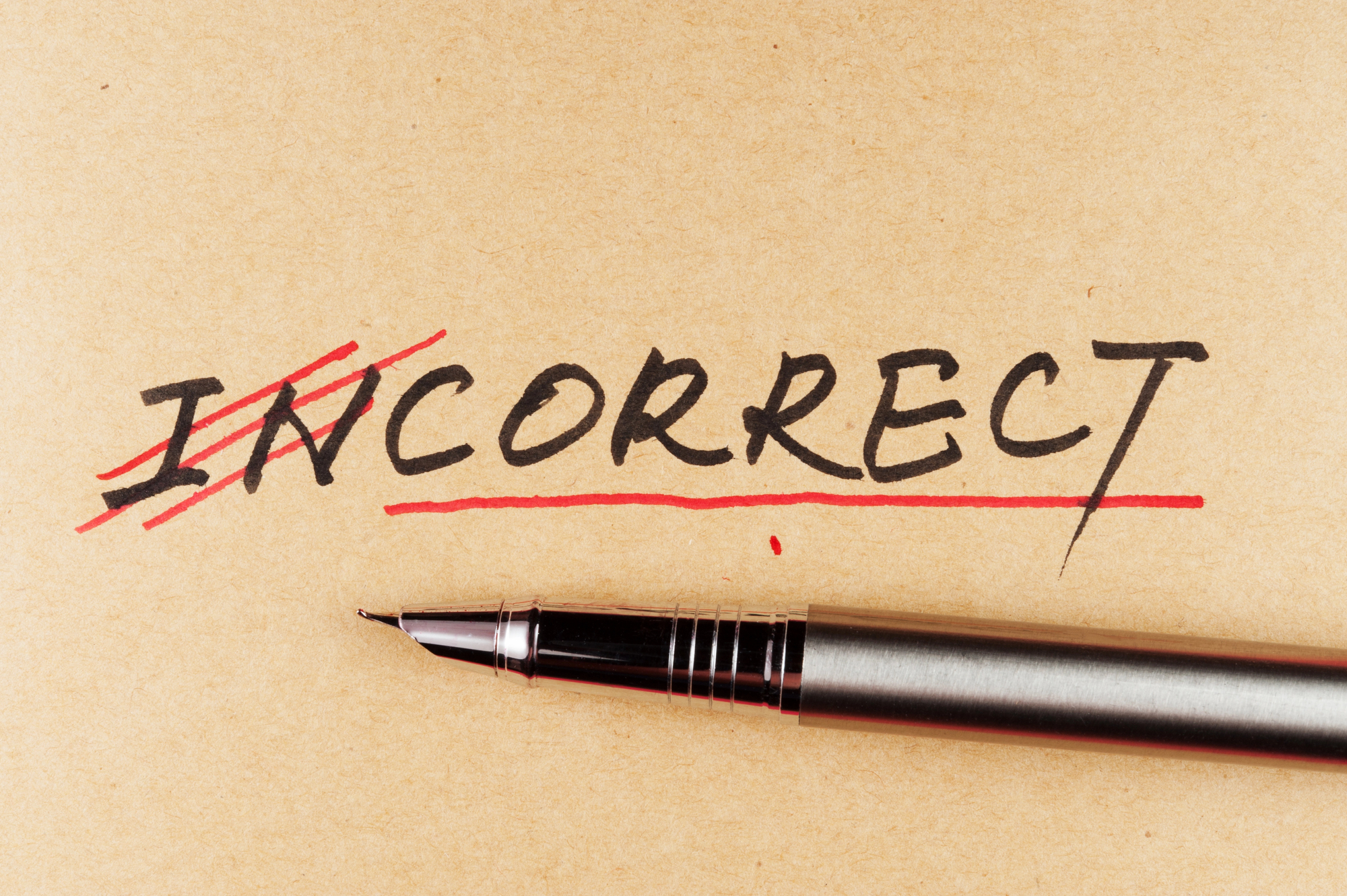The word "incorrect" with the first two letters crossed out in red, and a pen beneath the word.