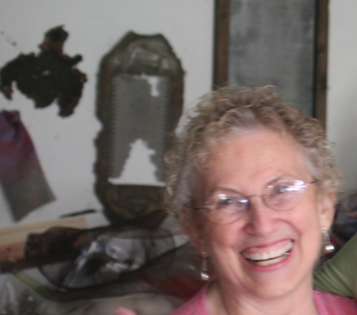Beth Beede IMG_3294 Beth Beede, smiling woman with objects on the wall behind her.